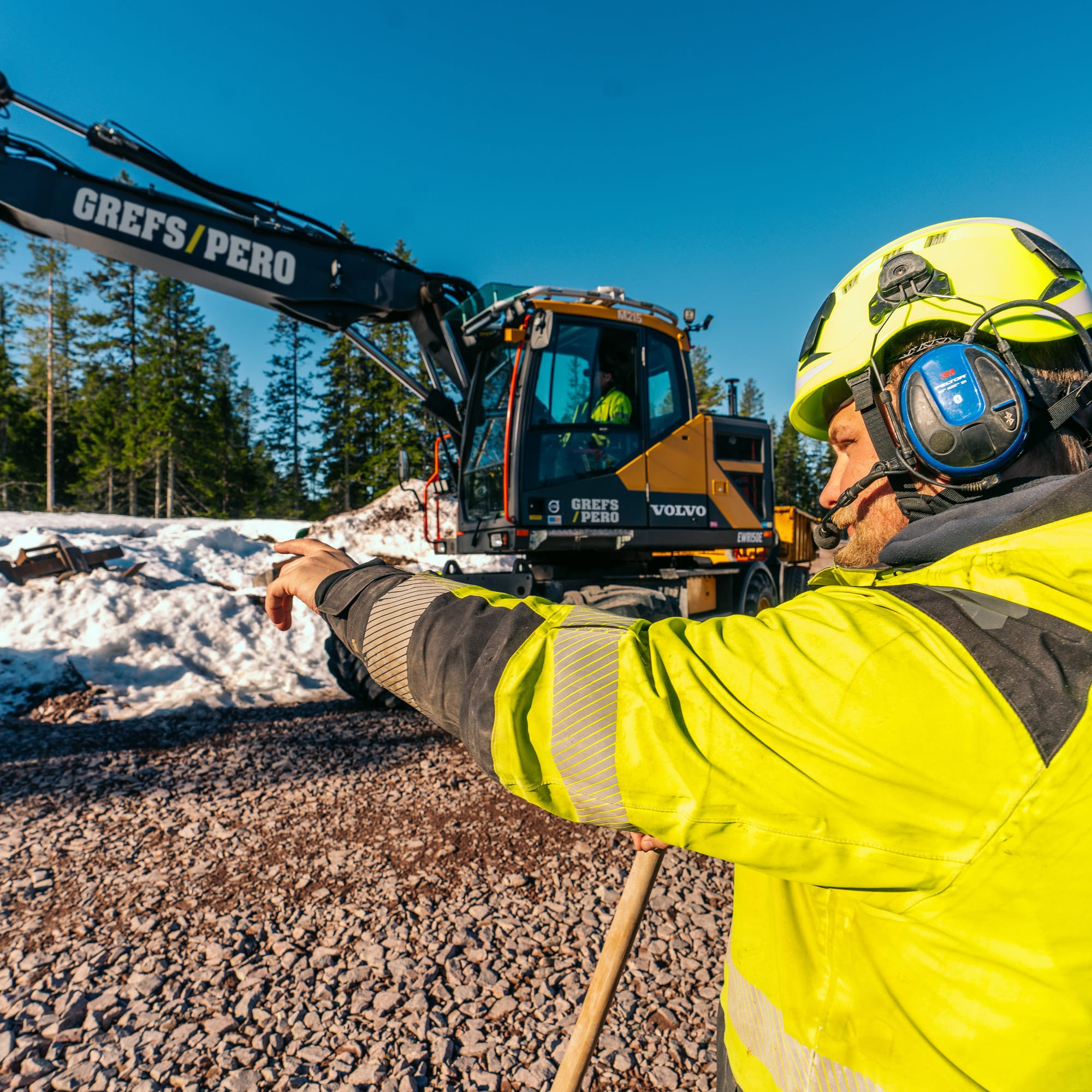 Man pekar och styr en grävmaskin.